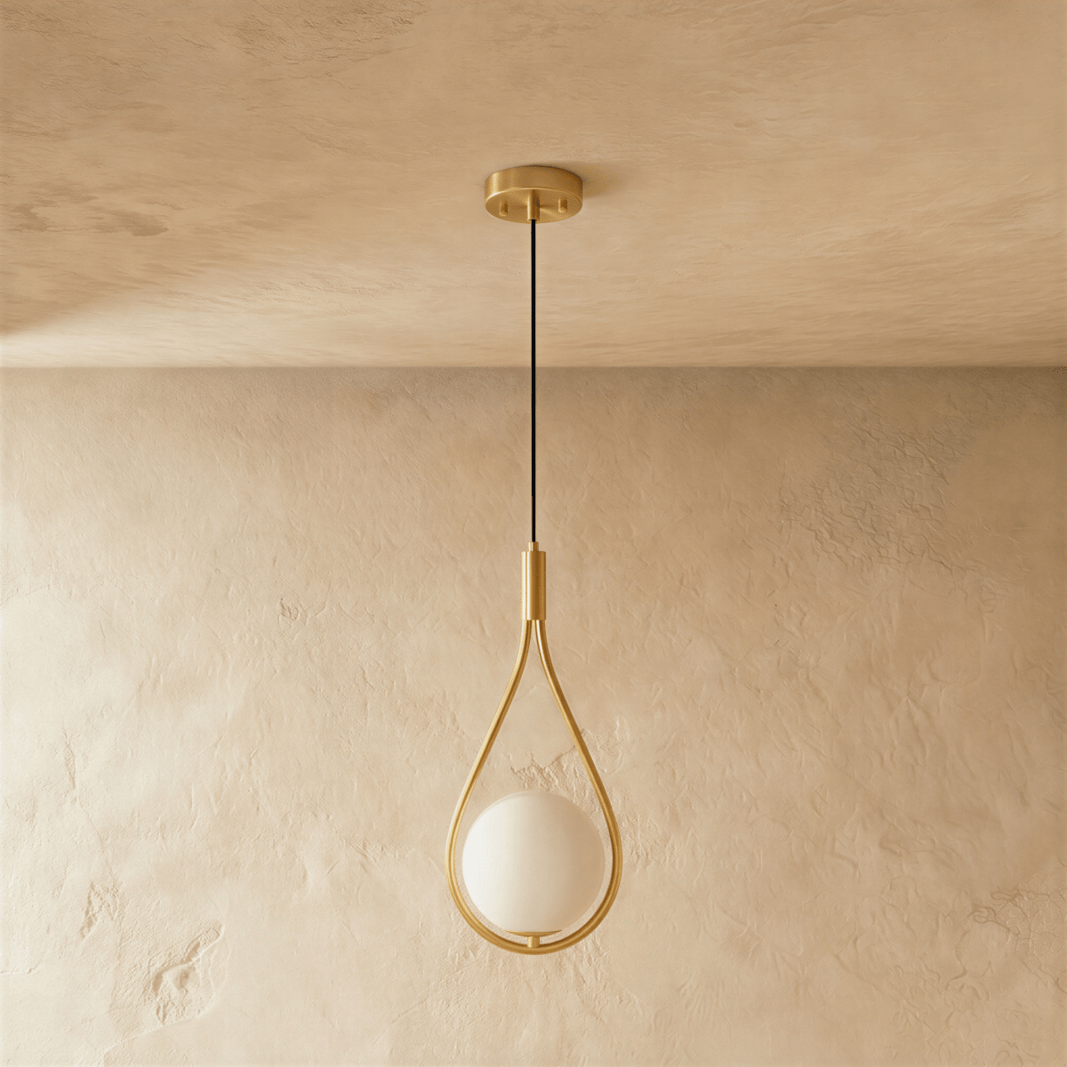 Clérachic teardrop pendant in brushed brass with an opal white globe, switched off, against a soft plaster wall and ceiling.