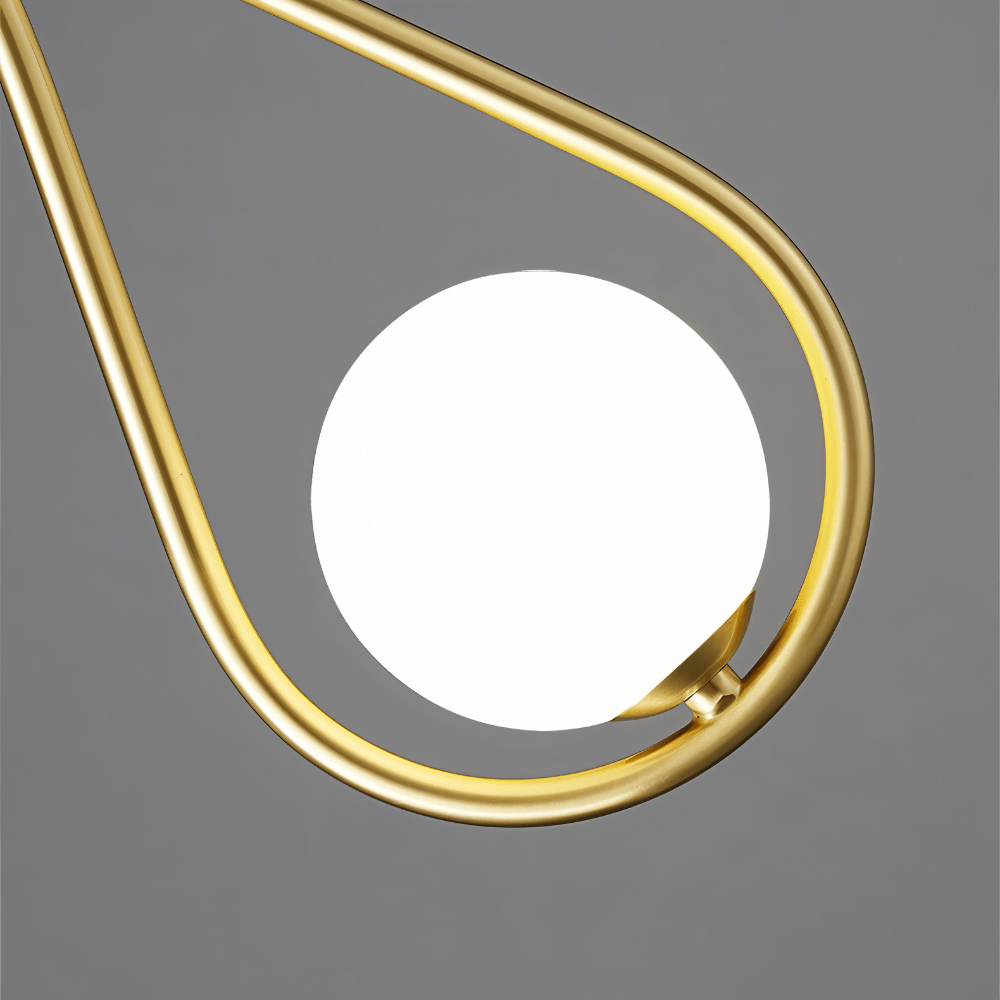 Close view of the Clérachic brass teardrop frame and its lit opal glass globe, showing the satin brass finish and the small clasp.