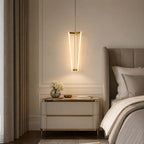 Hung beside a bed and a cream bedside chest, this Clérachic pendant lights a panelled bedroom wall with three slim glowing tubes.