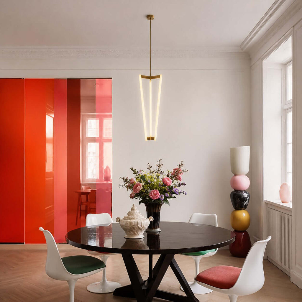 Above a round black table with white tulip chairs, this Clérachic pendant hangs in a white room with a bright red panel behind.