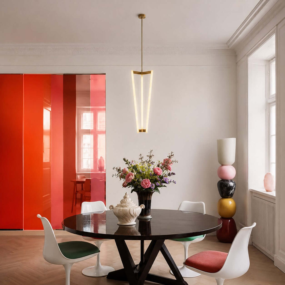 Above a round black table with white tulip chairs, this Clérachic pendant hangs in a white room with a bright red panel behind.