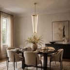 Over a set dining table with cream chairs and an abstract print on the wall, this Clérachic pendant hangs from a short brass rod.