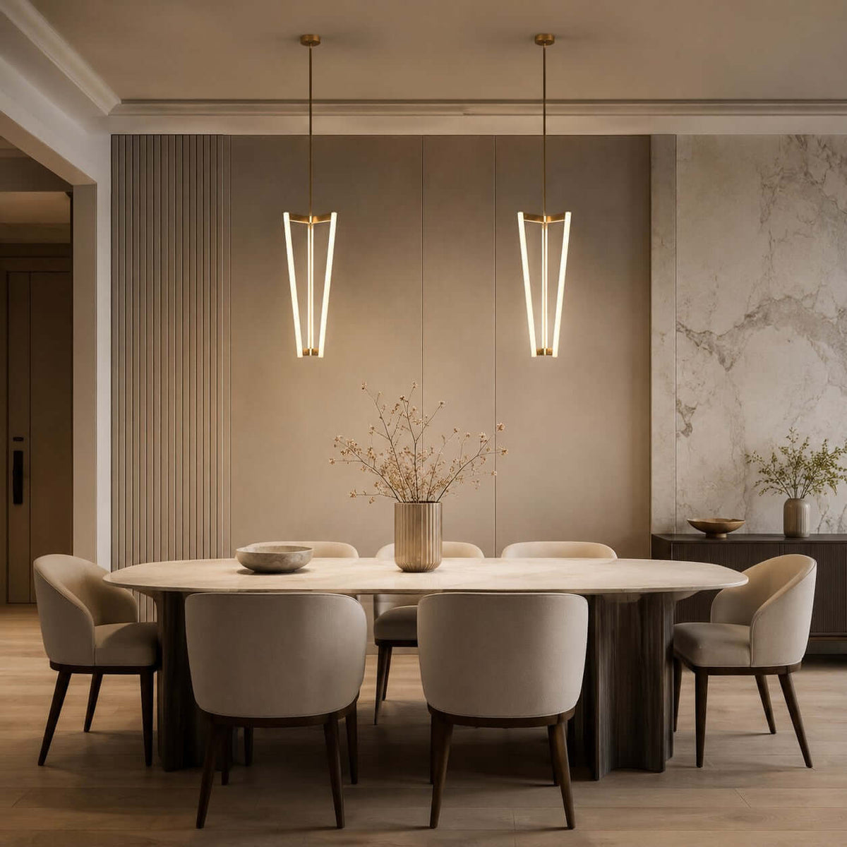A pair of Clérachic pendants hang side by side above a long oval dining table, in front of a fluted wall and marble panel.