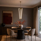 Over a round dark table with a vase of red autumn stems, this Clérachic pendant hangs against a dark wall and abstract print.