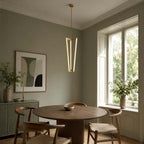 In a sage-green dining room with a round table and wishbone chairs, this Clérachic pendant glows beside a tall sash window.