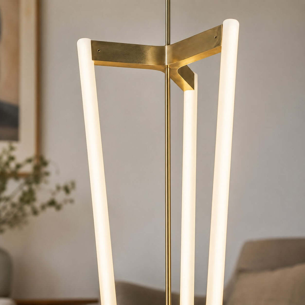 Close view of the brass bracket on this Clérachic pendant, where three frosted LED tubes meet at the central rod.