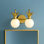Two-light Clérachic wall light in brass with opal glass globes, mounted on a blue wall above a gold-framed mirror.