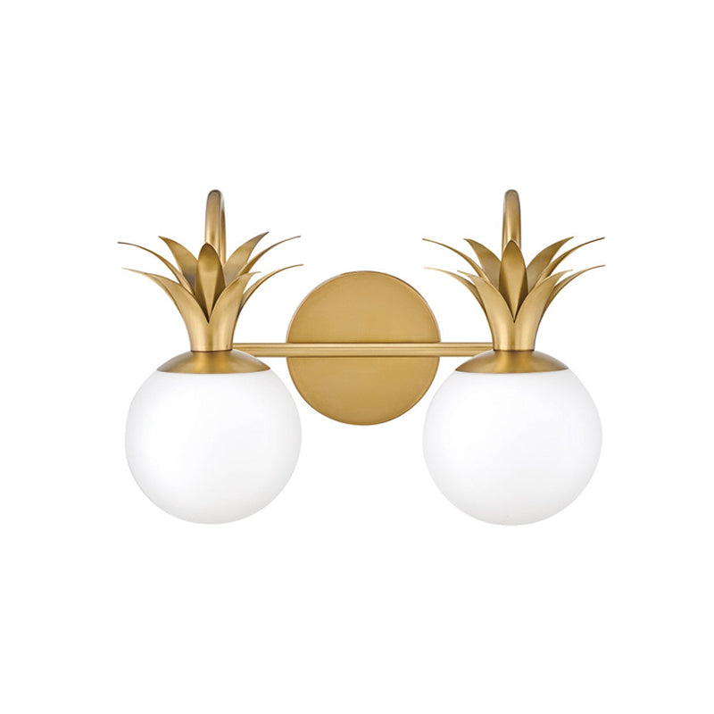 Cut-out view of the two-light version of this Clérachic wall light, with two white globes under brass pineapple-leaf crowns.