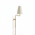 Brass Clérachic plug-in wall light with a curved arm and a tapered white fabric shade, hung on a plain white wall.