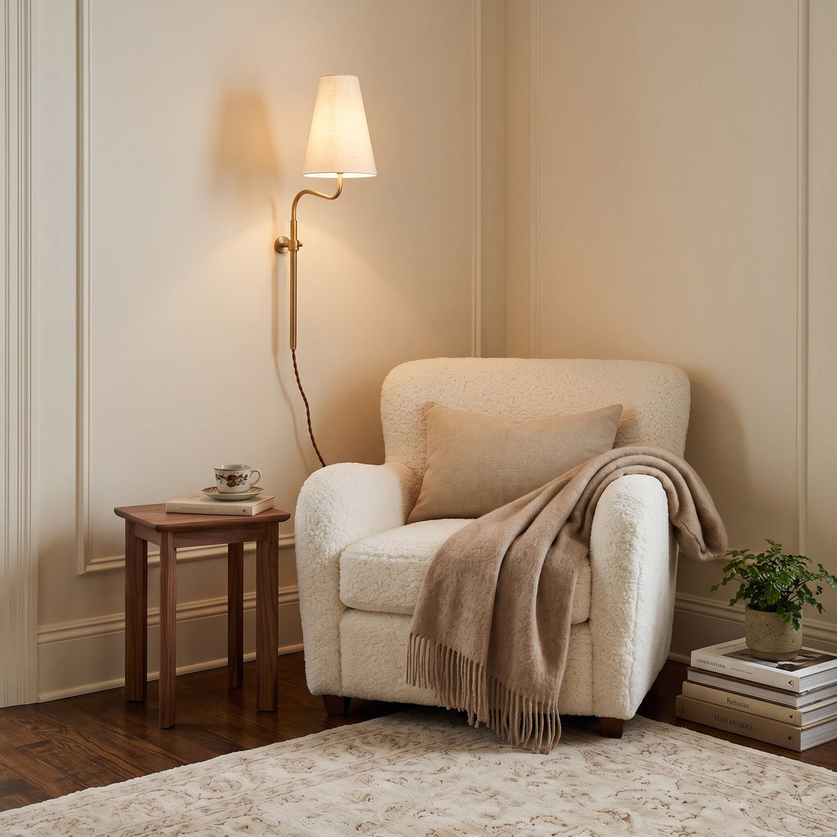 In a cream-panelled corner, this Clérachic brass wall light with a white shade glows above a boucle armchair and a small table.