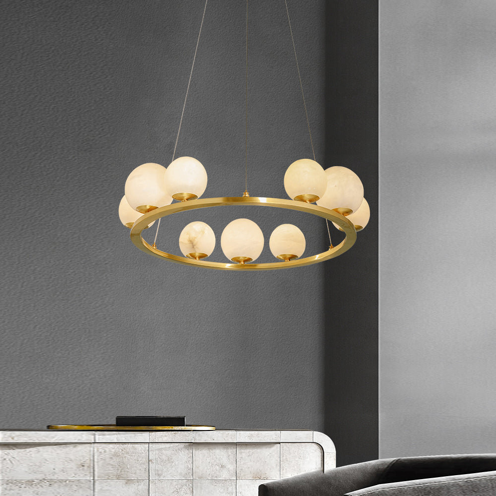 The Clérachic brass ring chandelier hanging against a charcoal wall above a stone-tiled sideboard in a living room.