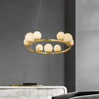 The Clérachic brass ring chandelier hanging against a charcoal wall above a stone-tiled sideboard in a living room.