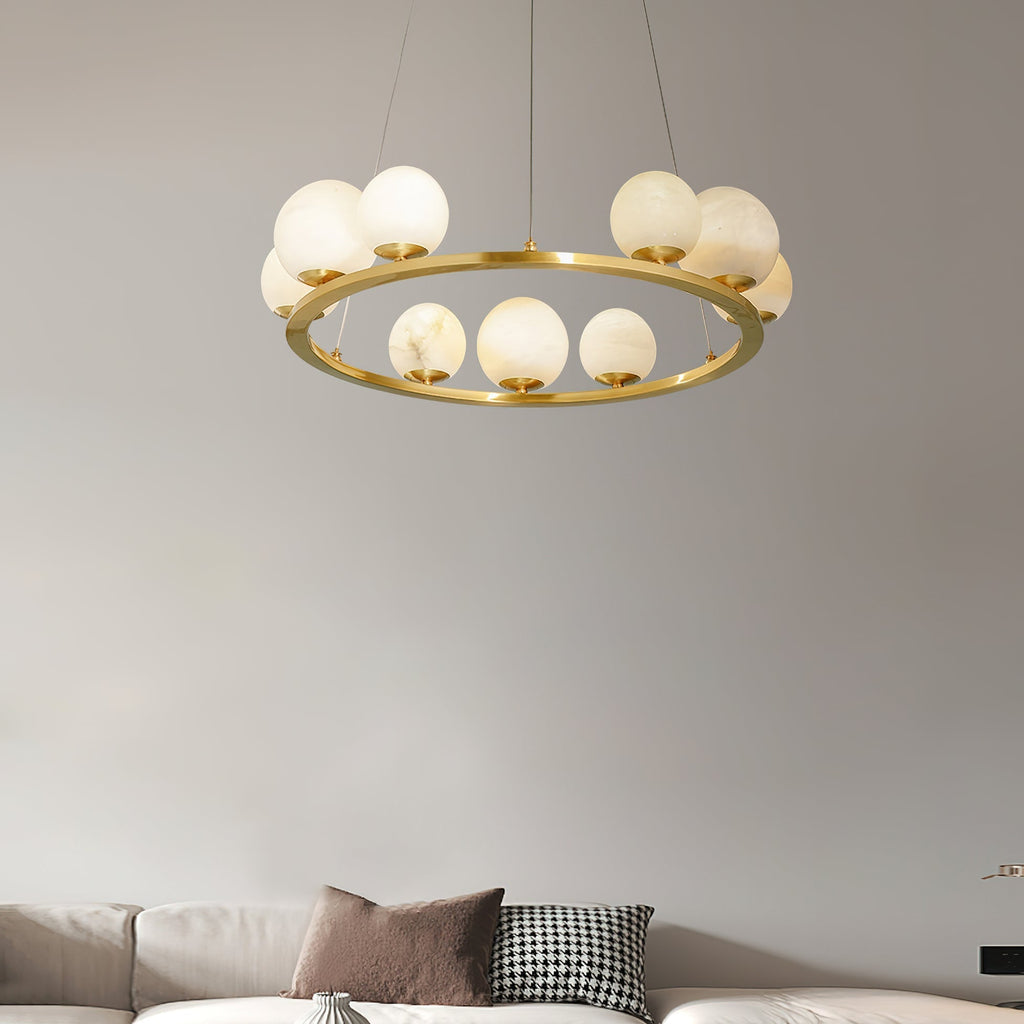 The Clérachic alabaster chandelier lit warm above a pale sofa, its globes glowing honey against a soft grey living-room wall.