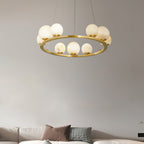 The Clérachic alabaster chandelier lit warm above a pale sofa, its globes glowing honey against a soft grey living-room wall.