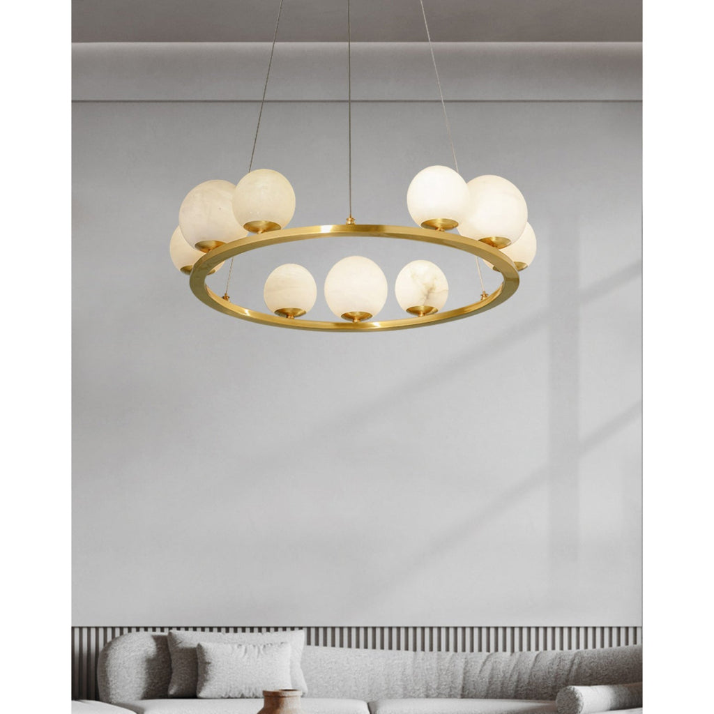 The Clérachic brass and alabaster chandelier over a bouclé sofa, catching daylight on a panelled wall in a quiet sitting room.