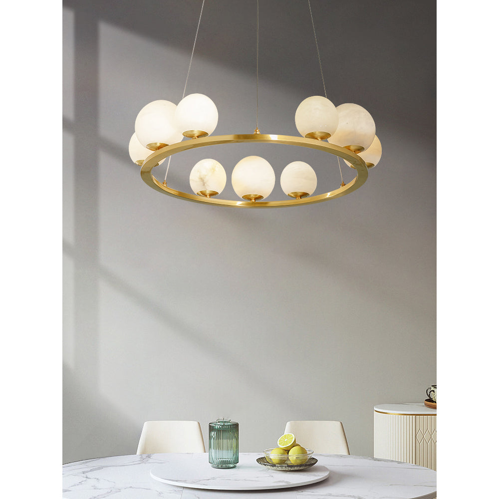 The Clérachic alabaster chandelier hung over a round marble dining table, sunlight tracing the wall behind it.
