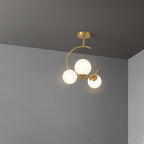 The Clérachic brass ring globe pendant in milky white glass, three softly lit spheres mounted close to a grey ceiling corner.