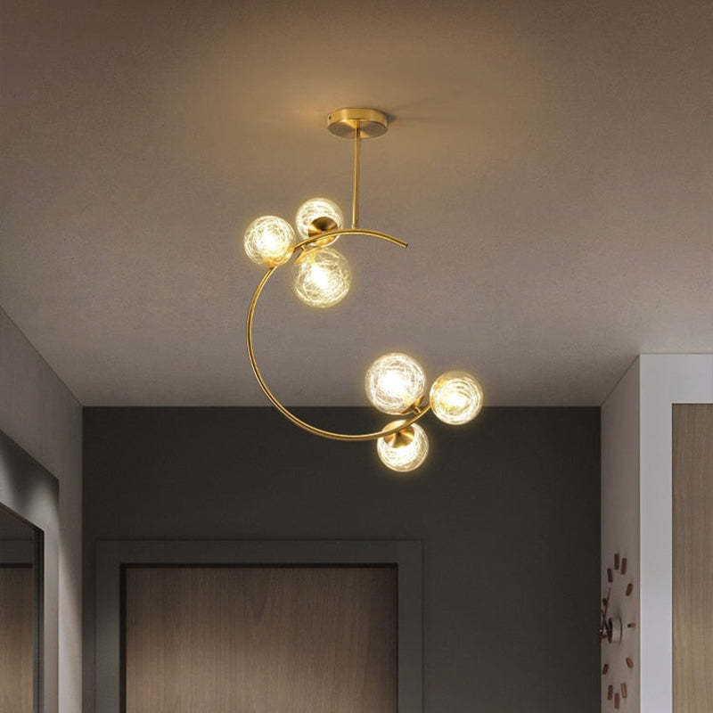 The Clérachic brass ring globe pendant in clear glass with six lit globes, hung in a hallway beside a mirrored door and woven baskets.