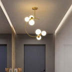 The Clérachic brass ring globe pendant in milky white glass, six glowing spheres lighting a hallway with strip-lit wood panelling.