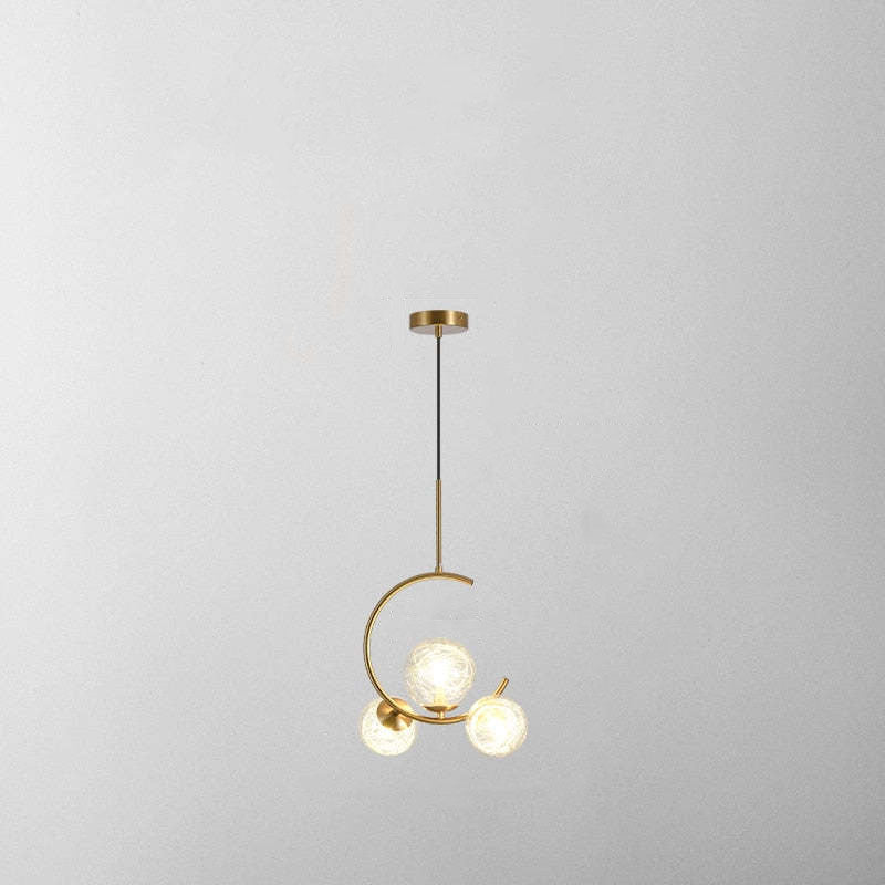 Product shot of the Clérachic brass ring globe pendant in clear glass, three lit globes on a plain grey backdrop showing the short ceiling rod.