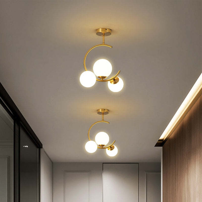 Two Clérachic brass ring globe pendants in milky white glass spaced along a hallway ceiling above two panelled doors.