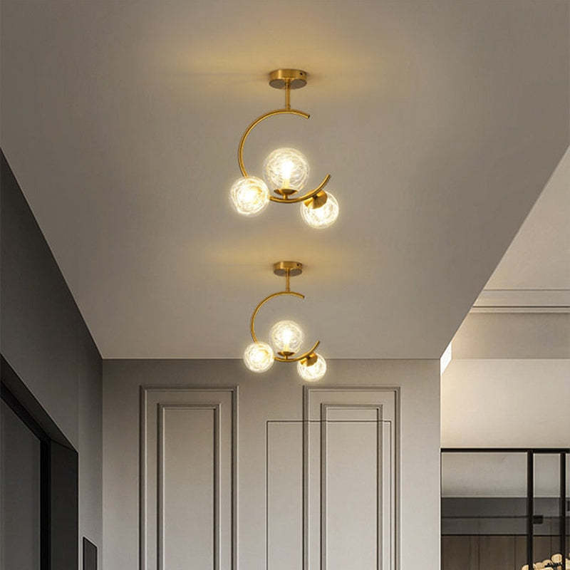 A pair of Clérachic brass ring globe pendants in milky white glass lighting a corridor with a mirrored wall to one side.
