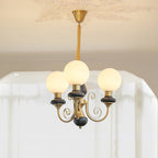 Black-stemmed Clérachic Brass Scrollwork Chandelier with three opal globes glowing under a plaster ceiling medallion.