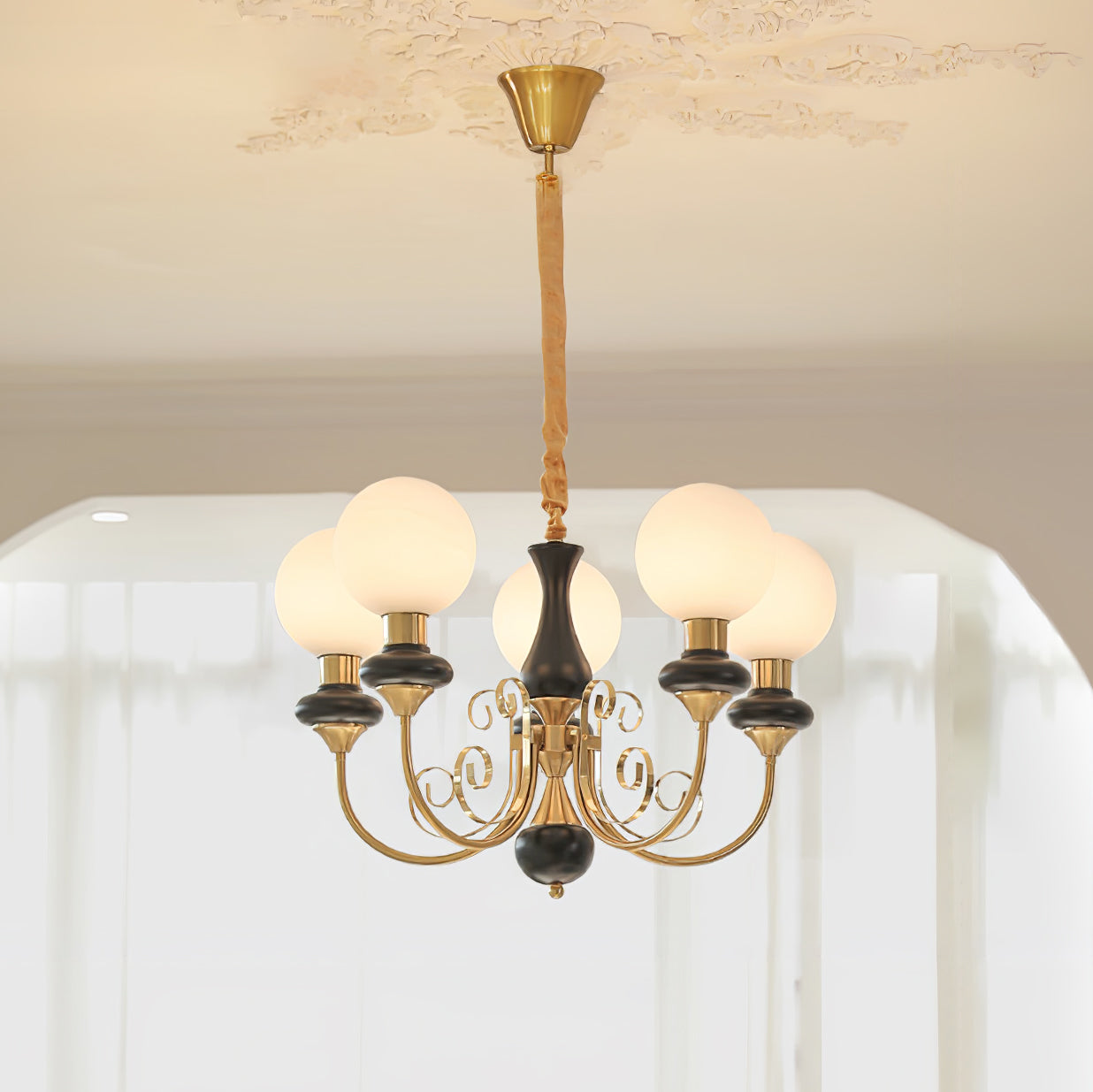 Clérachic Brass Scrollwork Chandelier in black, five opal globes lit beneath a decorative plaster ceiling rose.