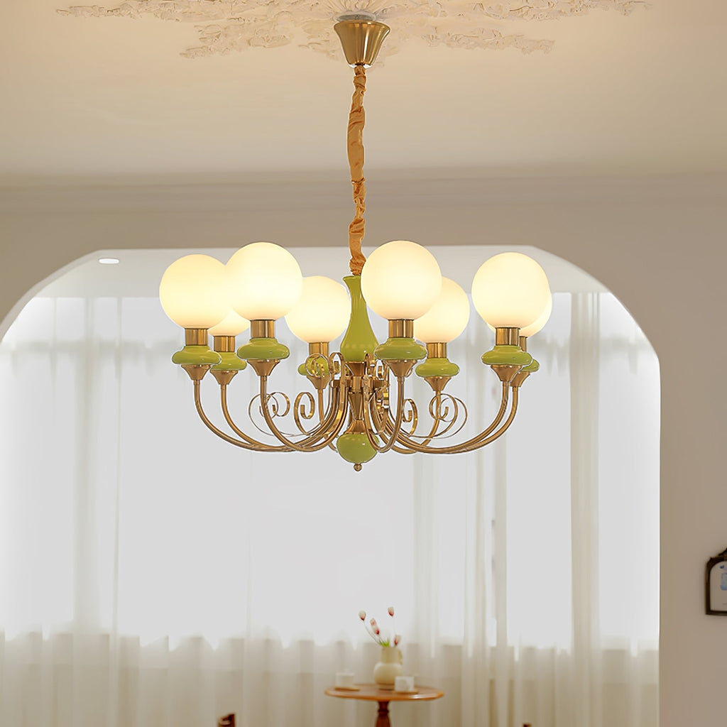 Eight-light green Clérachic Brass Scrollwork Chandelier lit in a hallway, hanging in front of an arched opening.