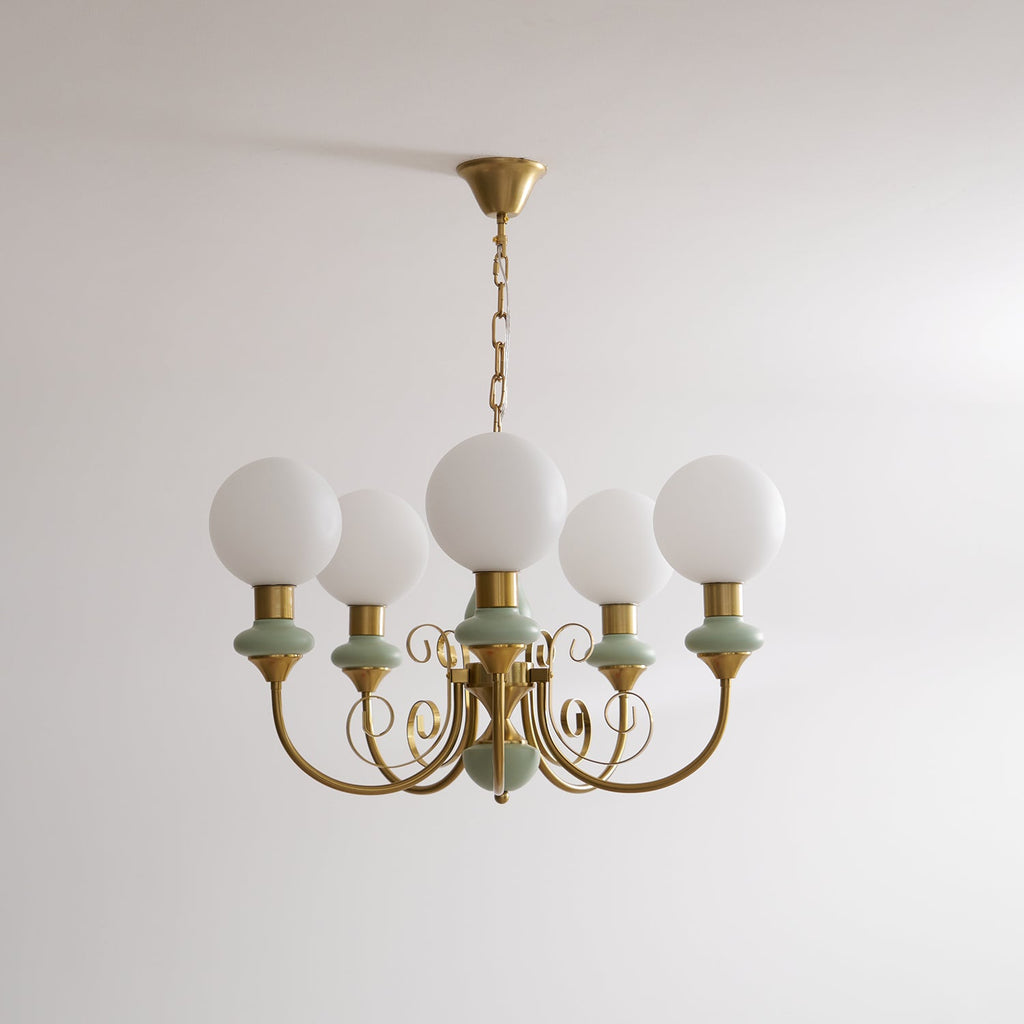 Clérachic Brass Scrollwork Chandelier in soft sage green, five lights hung unlit on a brass chain against a plain wall.