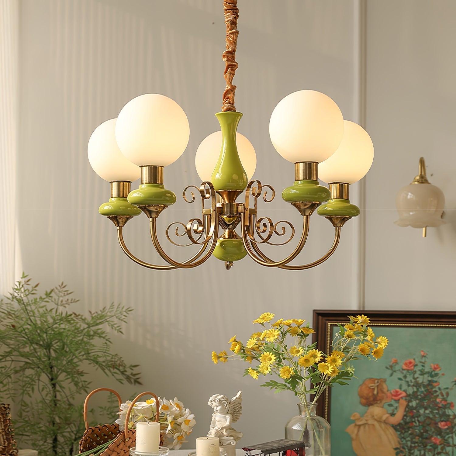 Green Clérachic Brass Scrollwork Chandelier lit above a styled console of daisies, candles and a framed painting.