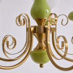 Close view of the Clérachic Brass Scrollwork Chandelier centre column, brass volutes curling around the glossy green stem.