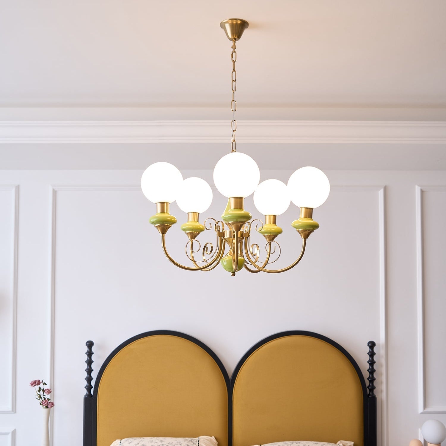 Clérachic Brass Scrollwork Chandelier lit above the bed, its five opal globes bright against white panelled walls.
