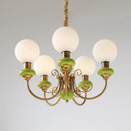 Clérachic Brass Scrollwork Chandelier in green on a grey studio backdrop, five opal globes and turned green collars.