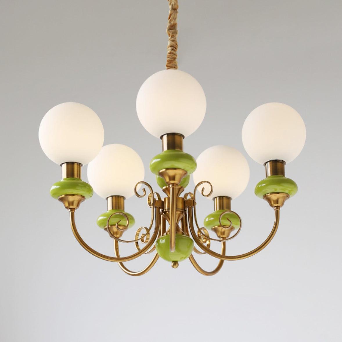 Clérachic Brass Scrollwork Chandelier in green on a grey studio backdrop, five opal globes and turned green collars.