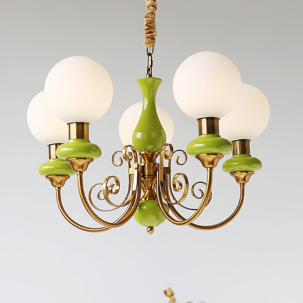 Clérachic Brass Scrollwork Chandelier in green, five lit globes on a grey backdrop with the chain and flex visible.