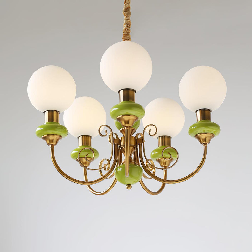 Clérachic Brass Scrollwork Chandelier in green seen close on grey, the flat brass volutes curling under each arm.