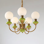 Clérachic Brass Scrollwork Chandelier in green seen close on grey, the flat brass volutes curling under each arm.