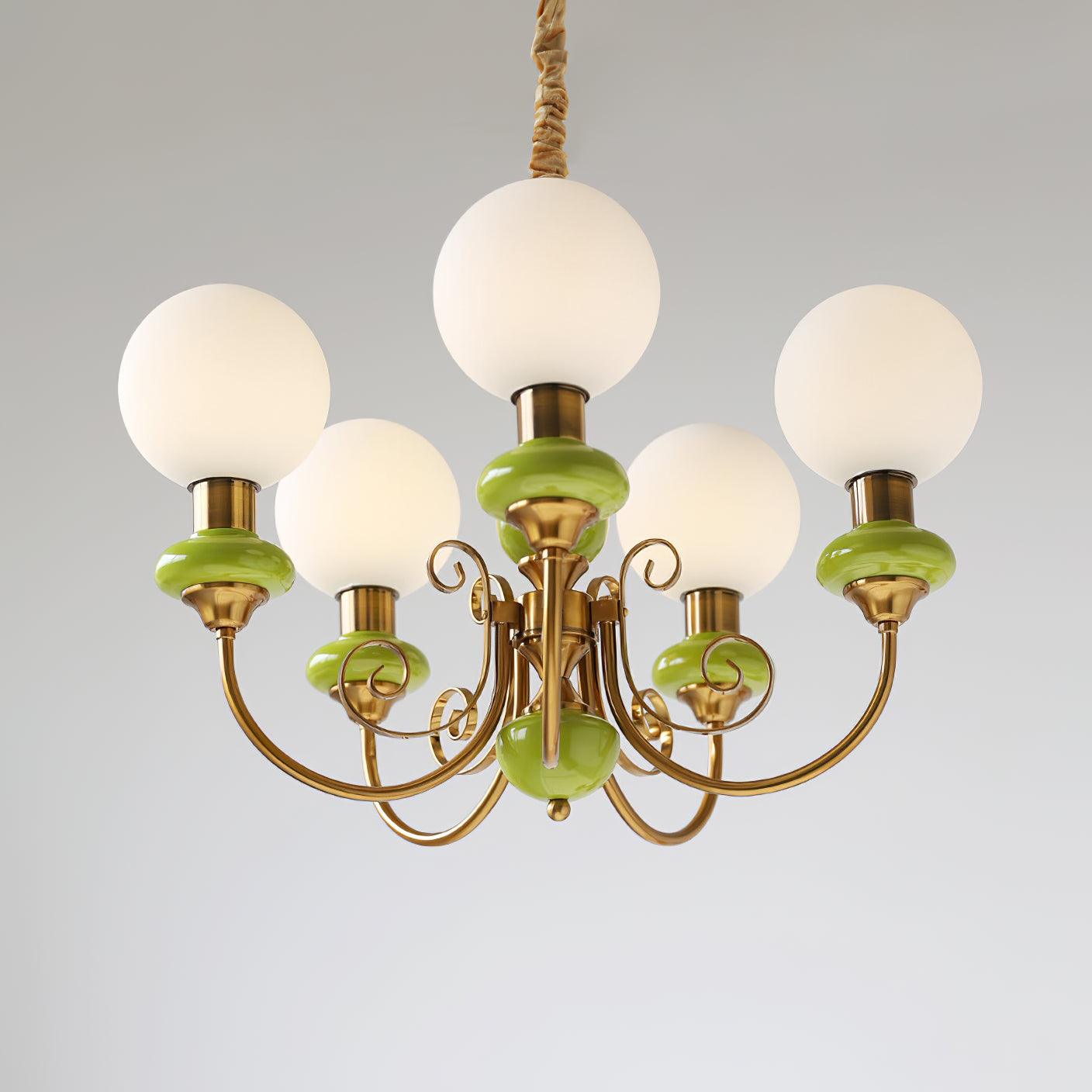 Clérachic Brass Scrollwork Chandelier in green seen close on grey, the flat brass volutes curling under each arm.