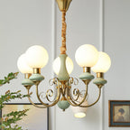 Clérachic Brass Scrollwork Chandelier in sage green, five lights lit beside a framed portrait on a panelled wall.