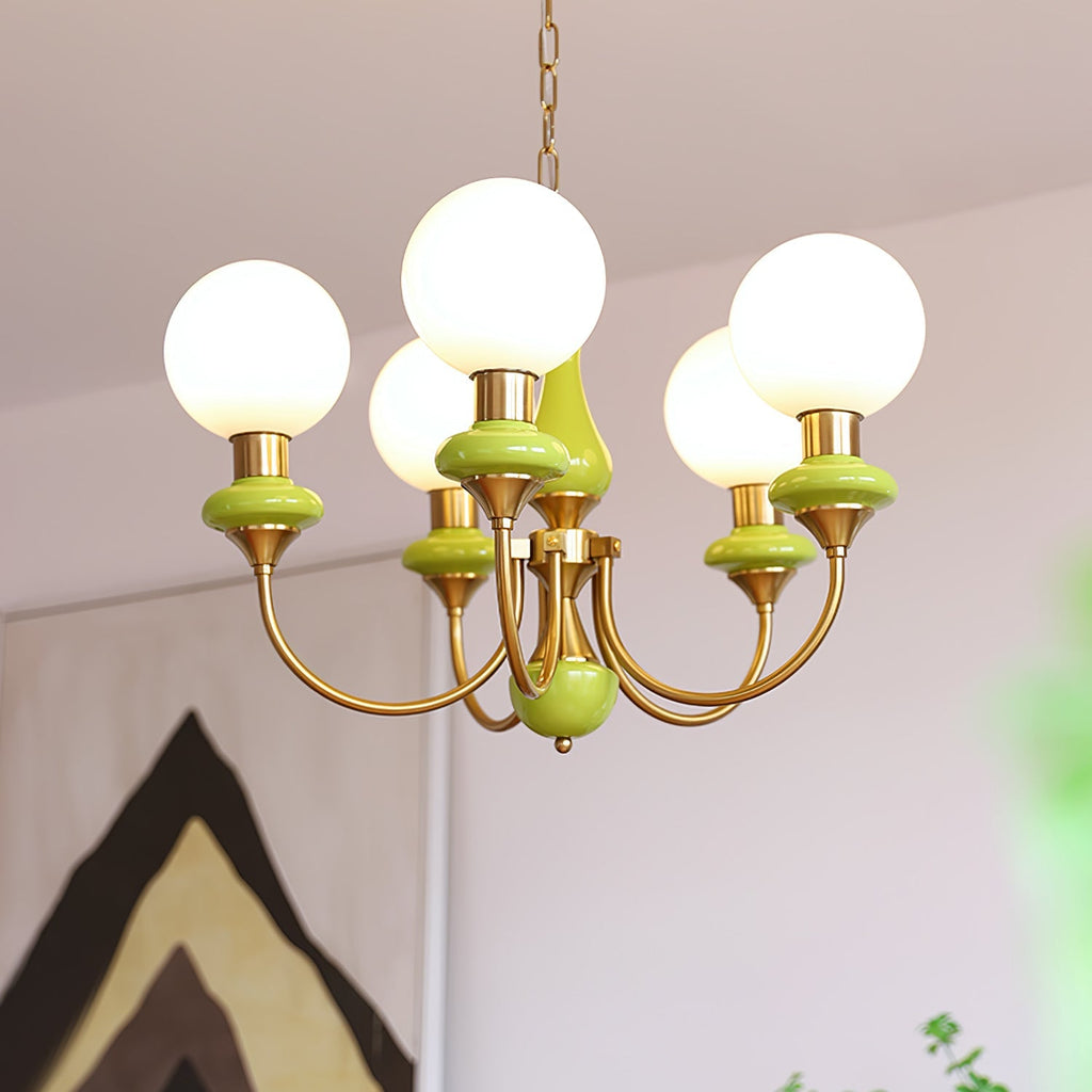 Green Clérachic Brass Scrollwork Chandelier lit in front of a bold geometric artwork, five opal globes glowing.