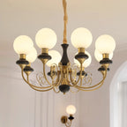 Clérachic Brass Scrollwork Chandelier in black, eight globes lit above a panelled wall with the matching sconce below.