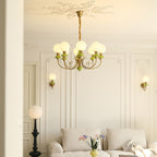 Green Clérachic Brass Scrollwork Chandelier lit in a living room with two matching sconces and a pale sofa below.