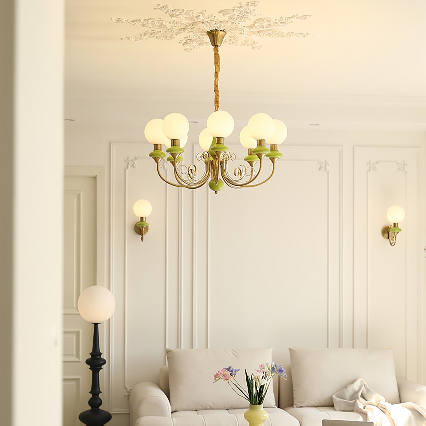 Green Clérachic Brass Scrollwork Chandelier lit in a living room with two matching sconces and a pale sofa below.