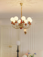 Eight-light Clérachic Brass Scrollwork Chandelier in red-brown, lit near tall panelled doors and a globe floor lamp.