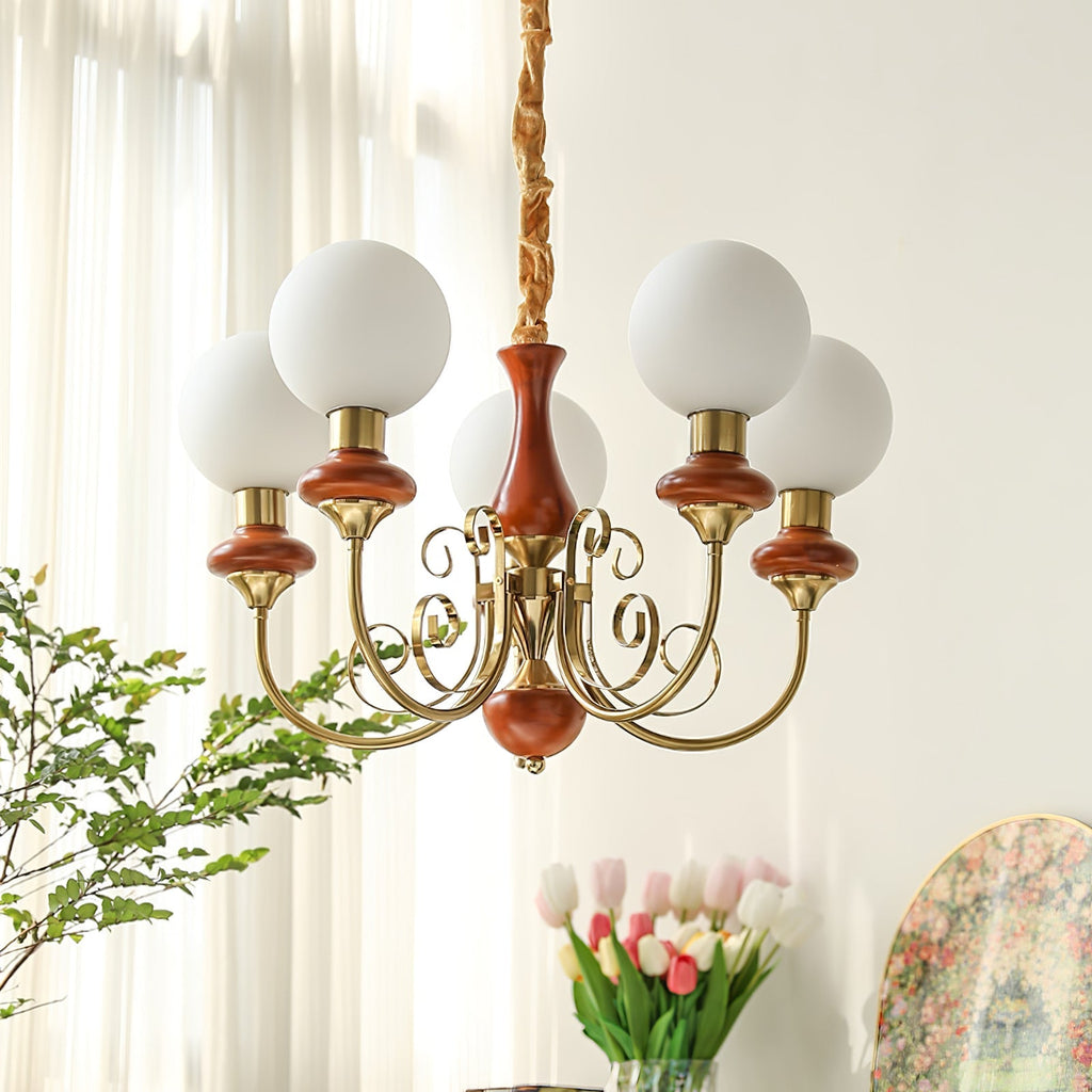 Red-brown Clérachic Brass Scrollwork Chandelier lit by a bright window, tulips and a framed print in the room beyond.