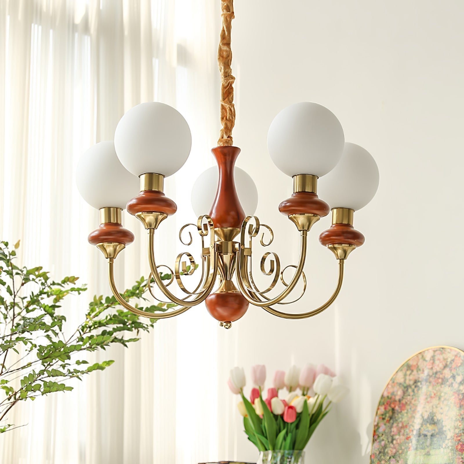 Red-brown Clérachic Brass Scrollwork Chandelier lit by a bright window, tulips and a framed print in the room beyond.