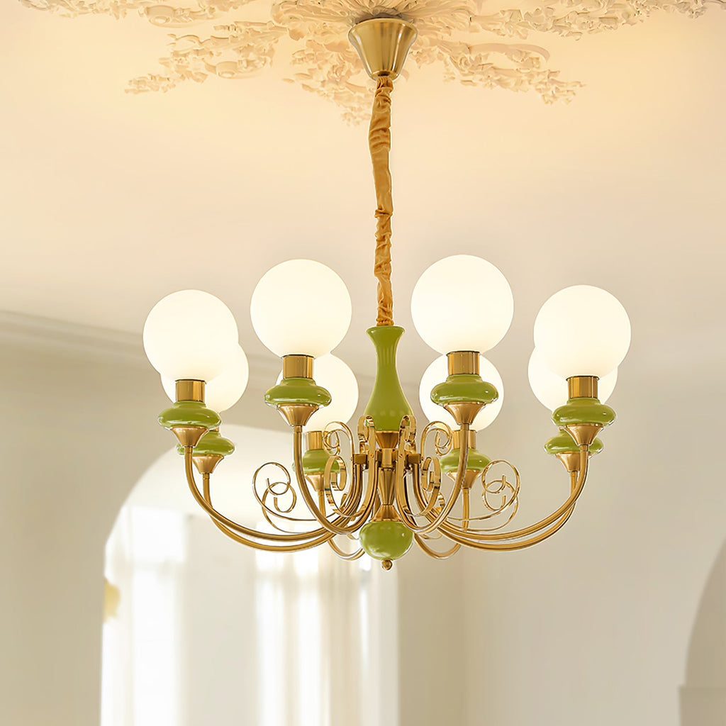 Green Clérachic Brass Scrollwork Chandelier in the eight-light size, lit under a carved ceiling rose beside an arch.