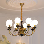 Clérachic Brass Scrollwork Chandelier in black, eight lit globes below a deep round plaster ceiling medallion.