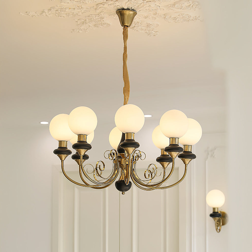 Eight-light Clérachic Brass Scrollwork Chandelier in black, lit above a panelled doorway with the matching sconce.